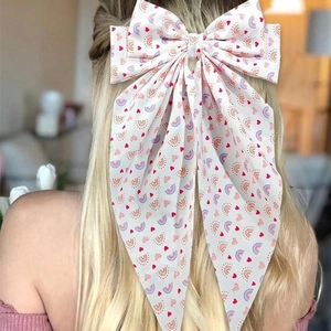 Elegant white bow hair clip with red heart prints and long ribbons worn by a blonde model