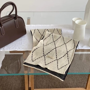 Detail showing hand made label on thick cream knit scarf with black diamond pattern