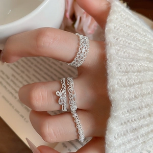 Macro detail of silver lace openwork ring with zircon bow on hand with knit sweater