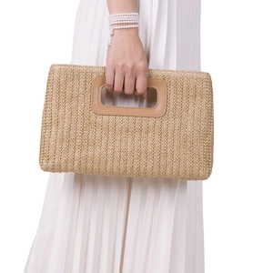 Close-up of khaki woven straw clutch with detachable chain on white pleated dress