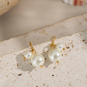 Boucles d'oreilles vintage en perles dorées posées sur une pierre de style français chic