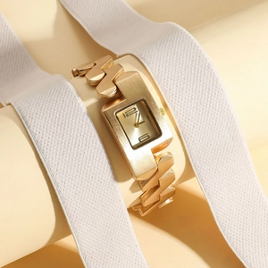 Close-up of rectangular gold fashion watch with vintage metal chain bracelet on stand