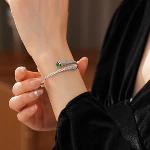 Close-up of silver open cuff bracelet with pavé zircons and a green emerald-cut stone