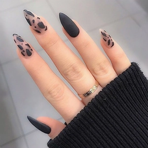 Detail of matte black stiletto press-on nails with leopard print and pointed shape