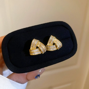 Macro detail of gold triangle stud earrings featuring micro-pave cubic zirconia crystals