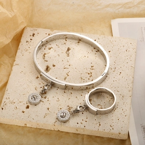 Detailed shot of silver Roman numeral jewelry set with zircon charms on beige stone