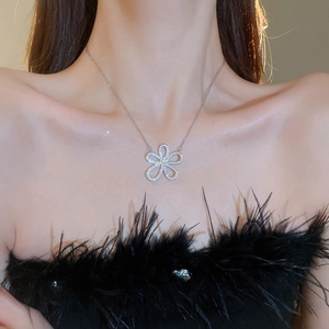 Close-up of a sparkling silver flower pendant necklace worn on a woman's collarbone