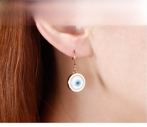 Gros plan d'un mannequin portant des boucles d'oreilles œil porte-bonheur or rose