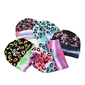 Top view of five leopard print knit beanies with colorful tie-dye folded cuffs