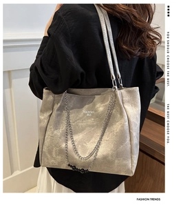 Close-up of silver tote bag with metallic texture and chain detail shown on a model shoulder