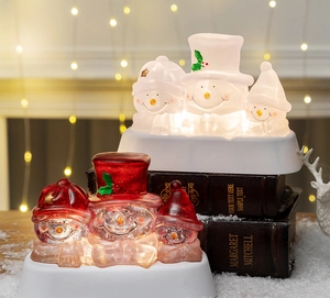 Luminous snowman figurines with warm LED light on vintage books and decorative snow