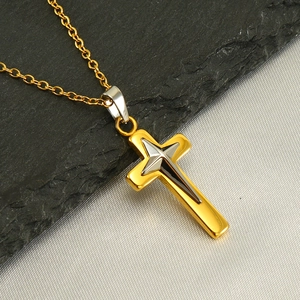 Pendentif croix bicolore en or 18 carats et argent sur pierre et tissu rustiques