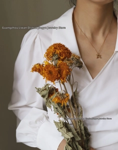Close-up of golden balloon dog pendant necklace worn by a model on a subtle chain