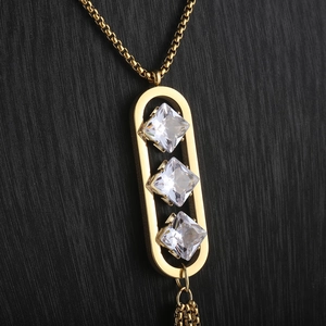 Detail of gold titanium tassel necklace with hollow oval pendant and zircon stones