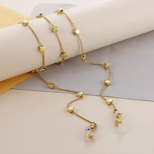 Detailed view of gold star charms on a stainless steel eyeglass chain over a minimal background