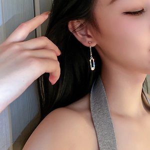 Close-up of elegant gold tassel earrings with glittering diamonds on a female model