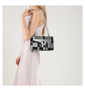 Detail of crossbody bag featuring diamond buckle and silver chain on plaid fabric