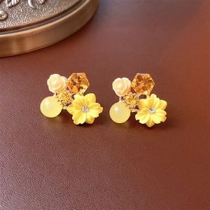 Detailaufnahme der gelben Blumenohrringe mit Bernsteinperlen und rosa Rosen auf Leder