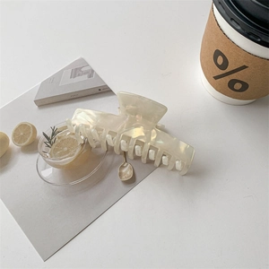 Macro detail of glossy pearlescent acetate hair claw clip in elegant lifestyle setting