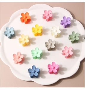 Close-up of 14 small matte flower hair clips in various colors displayed in a floral tray