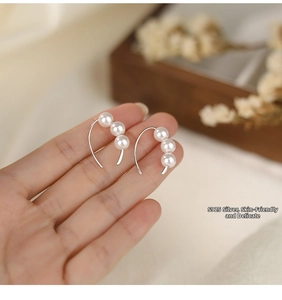 Detail of S925 sterling silver earrings with three vertical pearls in a warm lifestyle setting