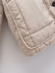Detailed macro view of quilted texture and reinforced pocket on beige cotton jacket