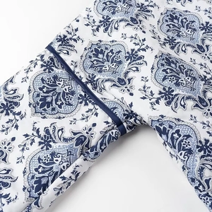 Macro detail of blue and white paisley print fabric with premium navy blue piped edges