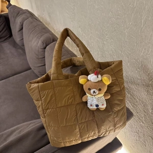 Detail of caramel quilted tote bag with soft puffer fabric and cute bear pendant