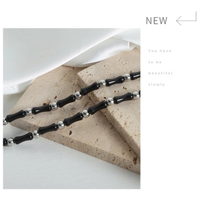 Detailed shot of black bamboo-shaped beads with silver metal spacers on a beige stone slab