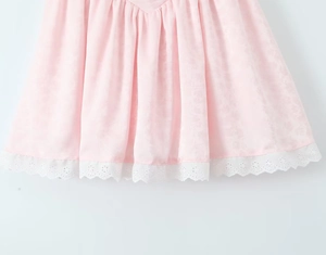 Détail de l'ourlet de robe en satin rose avec bordure en dentelle blanche ajourée