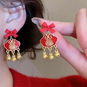 Close-up of festive red lion dance earrings with gold bells and bow for New Year
