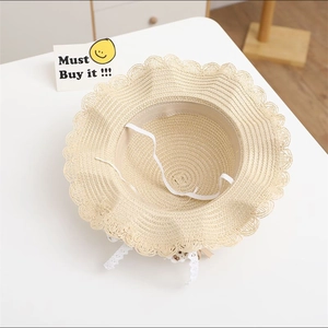 Detailed close-up of straw sun hat for girls with delicate lace trim and cute bear patch