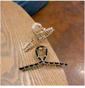 Detail of woven chain hair claws with white and black ribbons on a wooden surface