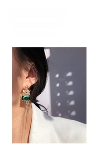 Detailed view of vintage gold drop earring with large rectangular emerald green zircon stone