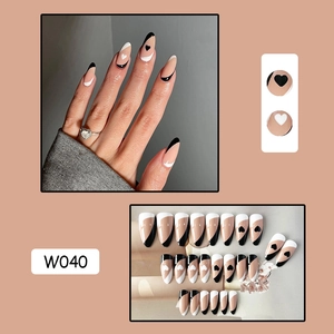 Detailed view of nude press-on nails with black and white heart motifs and French tips
