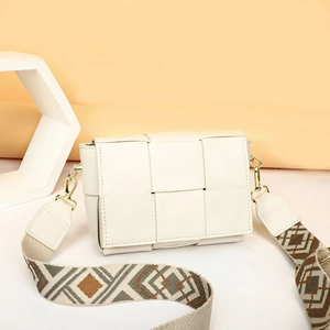 Detailed texture of off-white woven leather bag with geometric patterned wide strap