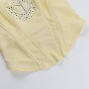 Détail d'un corset jaune avec découpe en cœur ornée de strass et fermeture éclair