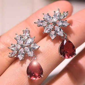 Macro detail of pear-shaped red zircon earrings with floral marquise crystal studs