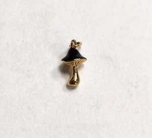 Detailed view of a gold-colored mushroom pendant with black enamel cap and link ring