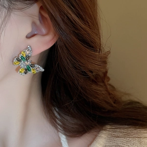 Close-up of model wearing butterfly drop earrings with colorful sparkling crystals