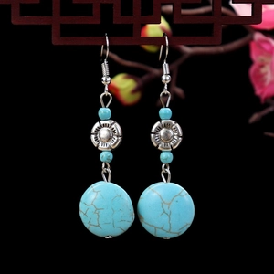 Detailed close-up of retro bohemian turquoise earrings with ethnic floral silver spacers