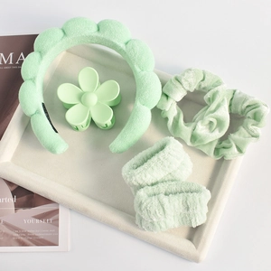 Mint green hair accessory set with sponge headband and velvet scrunchies on a white tray