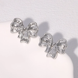Macro shot of silver bow stud earrings with detailed brushed metallic texture