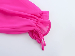 Détail d'une manche en mousseline rose avec poignets à volants et cordons pour un look féminin