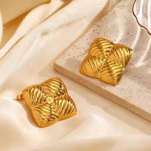 Vintage gold square earrings with radial textures on travertine and silk background