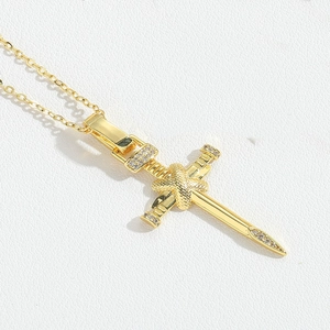 Close-up of gold sword and snake pendant necklace with shimmering zircon stones