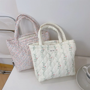 Close-up of quilted floral cotton tote bags with elegant embroidery and brand tag