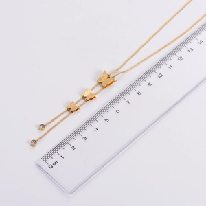 Golden butterfly necklace with tassels and rhinestones measured next to a ruler