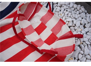 Detailed top view of the canvas tote bag showing interior lining, pocket and red stripes