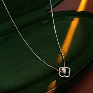 Close-up of silver flower pendant with inlaid gemstones in a luxury green velvet box